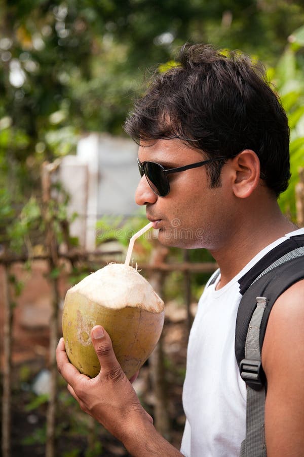 Happy indian man drinking coconut water