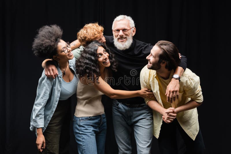 Happy interracial actors hugging bearded grey stock photo