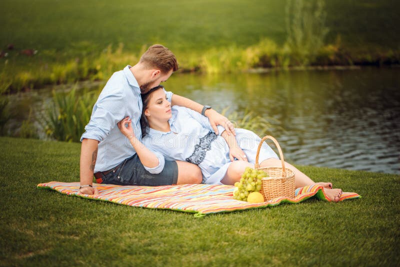 Happy joyful young family husband and his pregnant wife having fun together outdoors, at picnic in summer park stock photos Happy joyful young family husband and his pregnant wife having fun together outdoors, at picnic in summer park stock photos