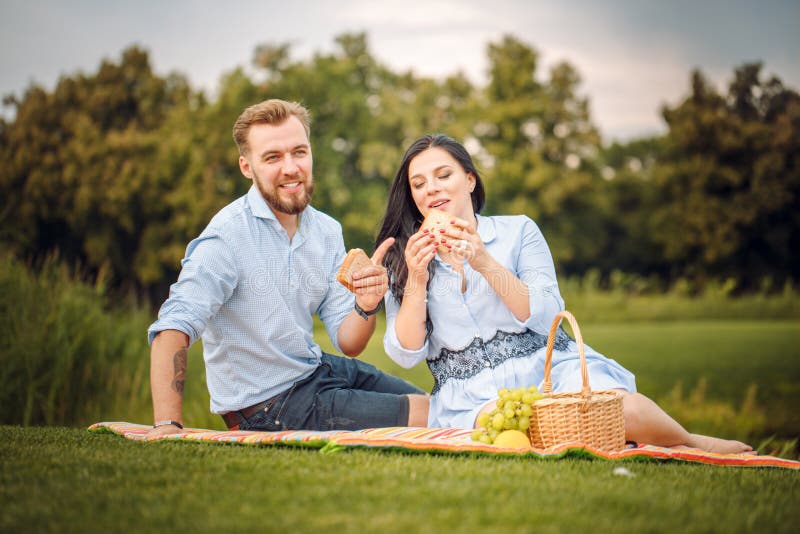 Happy joyful young family husband and his pregnant wife having fun together outdoors, at picnic in summer park stock image Happy joyful young family husband and his pregnant wife having fun together outdoors, at picnic in summer park stock image