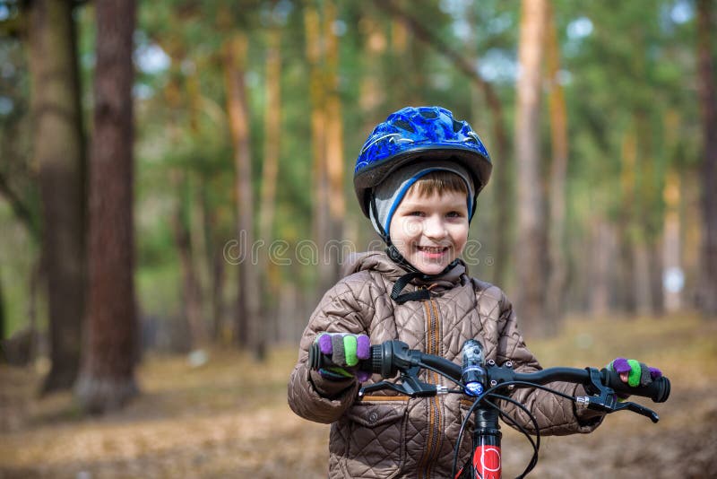 Happy kid boy of 3 or 5 years having fun in autumn forest with a bicycle on beautiful fall day. Active child wearing bike helmet. stock photography Happy kid boy of 3 or 5 years having fun in autumn forest with a bicycle on beautiful fall day. Active child wearing bike helmet. stock photography