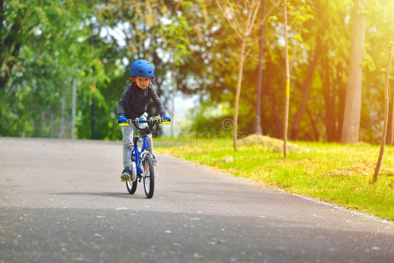 Happy kid boy of 5 years having fun in outdoor park with a bicycle on beautiful spring day. Active child making sports. Safety royalty free stock image Happy kid boy of 5 years having fun in outdoor park with a bicycle on beautiful spring day. Active child making sports. Safety royalty free stock image