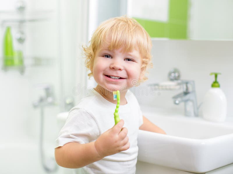 Felice ragazzo o bambino lavarsi i denti in bagno.