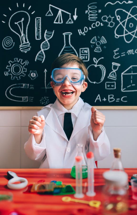 Portrait of happy little scientist with glasses laughing behind of red table with experiment elements. Portrait of happy little scientist with glasses laughing behind of red table with experiment elements