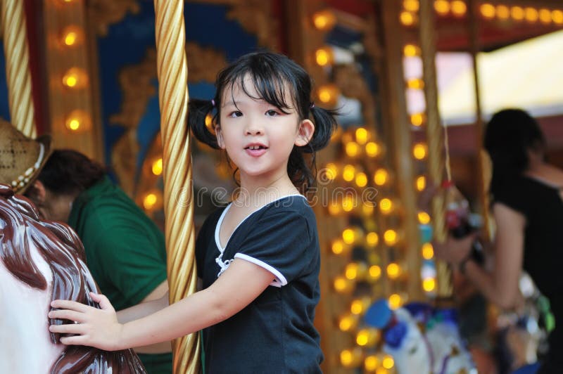 Happy asian little kid riding a merry-go-round in the amusement park. Happy asian little kid riding a merry-go-round in the amusement park