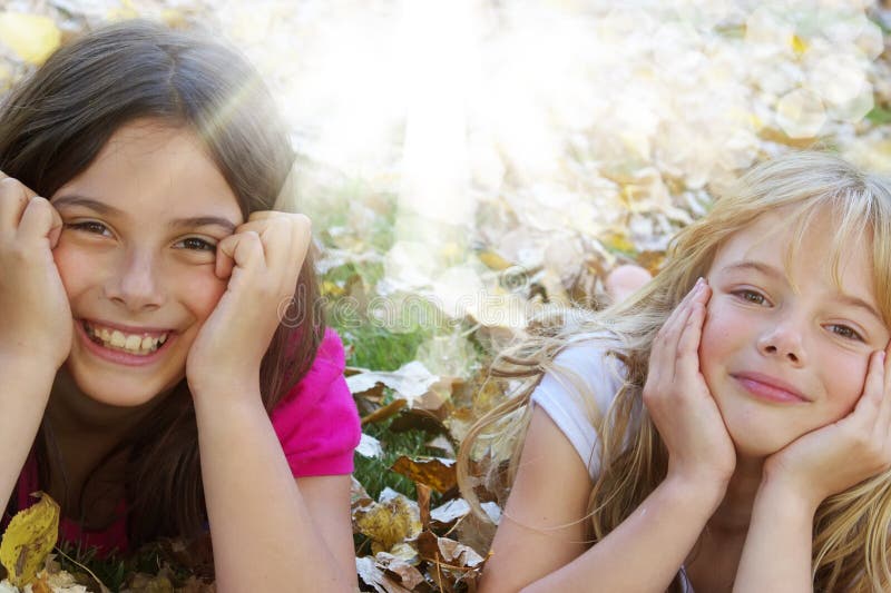 Dos feliz las chicas acostada abajo en otono hojas.