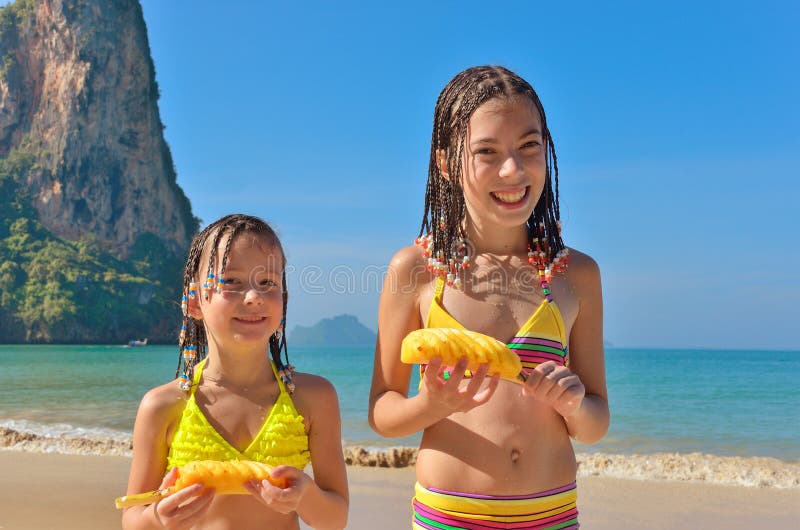 Happy kids on beach family vacation, children eating pineapple tropical fruit