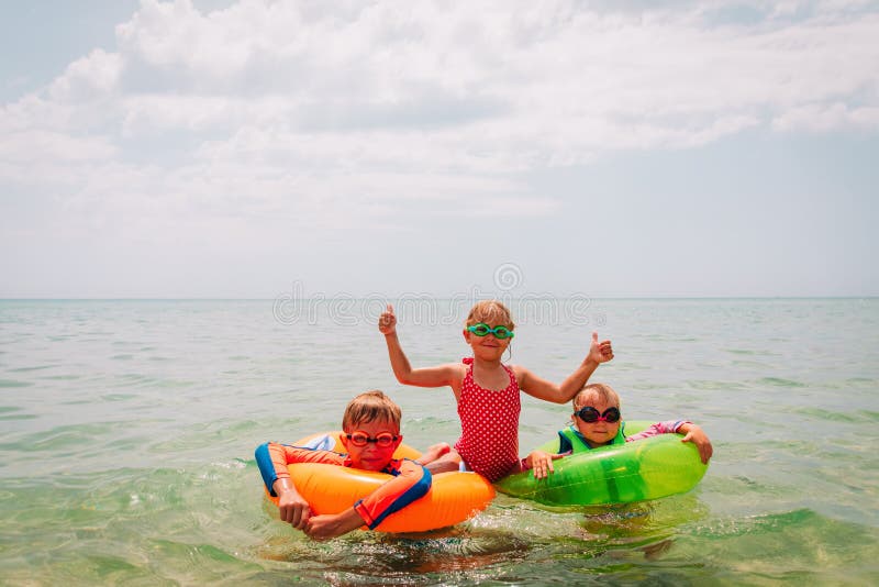 Happy kids-boy and girls-enjoy swimming at beach