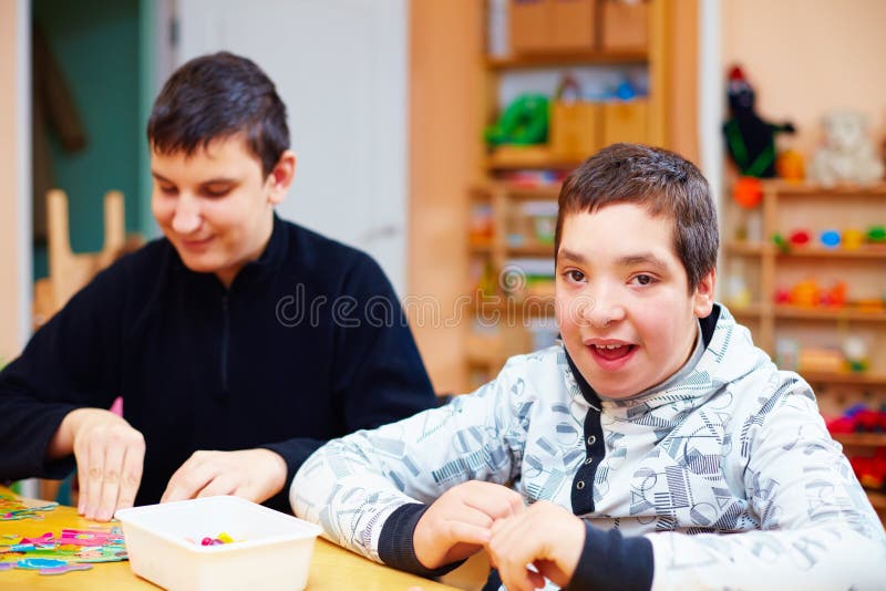 Portrait of happy kids with disability develop their fine motor skills at rehabilitation center for kids with special needs