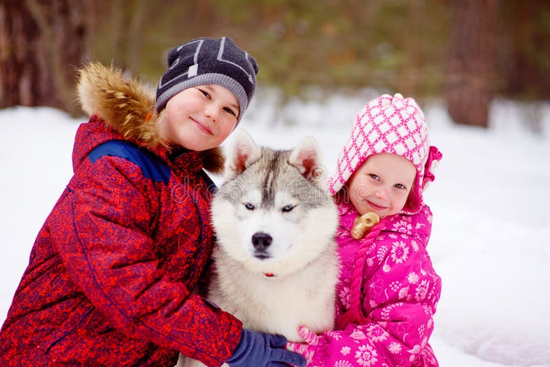 Happy kids embracing hasky dog in winter park