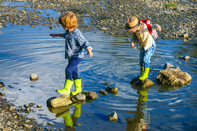 Happy kids enjoying on beautiful river. Little toddlers on summer day. Camping fun. Little Tourists in the camp at rest, enjoy nature