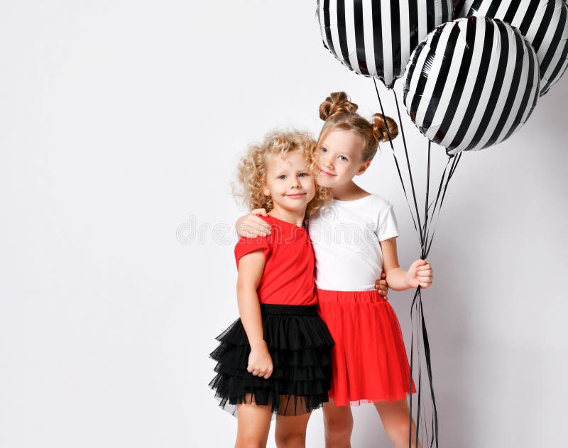 Happy kids girls sisters in red and black skirts celebrate birthday are screaming singing songs playing celebrating air balloons stock photo Happy kids girls sisters in red and black skirts celebrate birthday are screaming singing songs playing celebrating air balloons stock photo