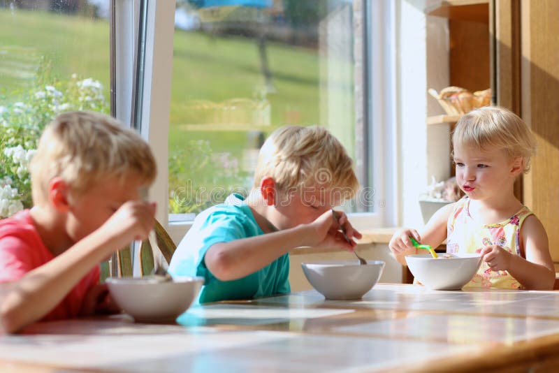 Happy kids having healthy breakfast in the kitchen
