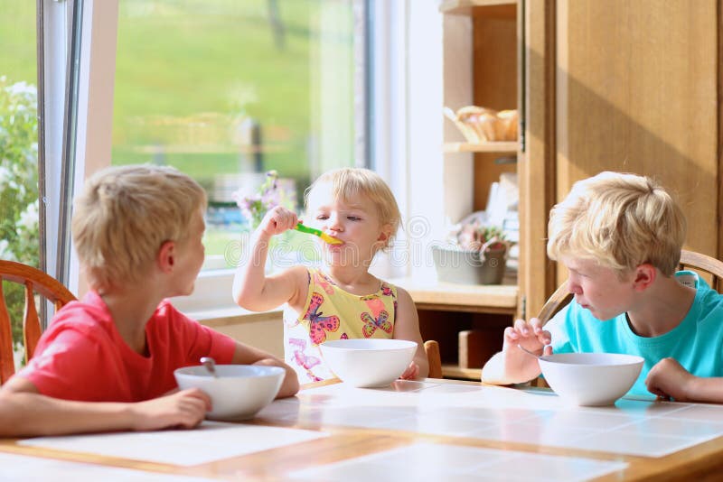 Happy kids having healthy breakfast in the kitchen