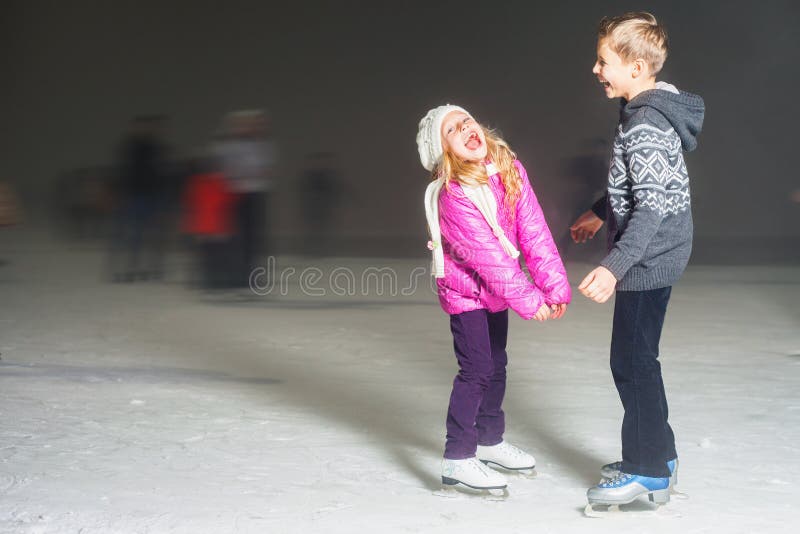 Happy kids laughing at ice rink outdoor, ice skating