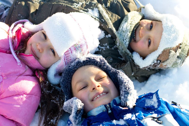 Tre felici, bambini sorridenti, laici all'aperto nella neve fresca in un freddo giorno d'inverno.