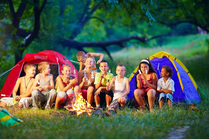 Happy kids roasting marshmallows on campfire