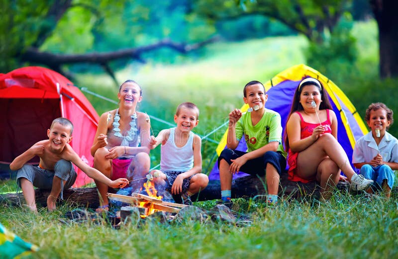 Happy kids roasting marshmallows on campfire