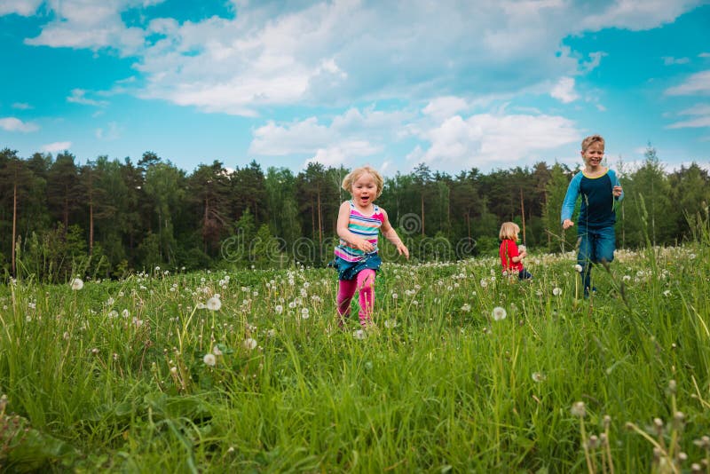 Happy kids run and play in summer nature, brother and sisters have fun