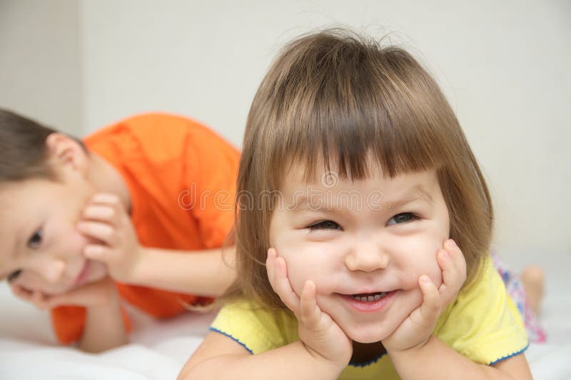 Happy kids, smiling little girl with cute cheeks and her brother royalty free stock photography Happy kids, smiling little girl with cute cheeks and her brother royalty free stock photography