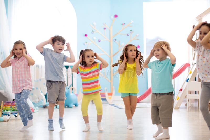 Happy Kinder, die Spaß beim Tanzen in einem sonnigen Raum im Kinderbetreuungs- oder Unterhaltungszentrum haben