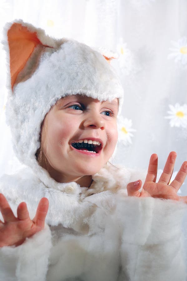 Little girl wearing a white kitten costume licking her fingers. Little girl wearing a white kitten costume licking her fingers