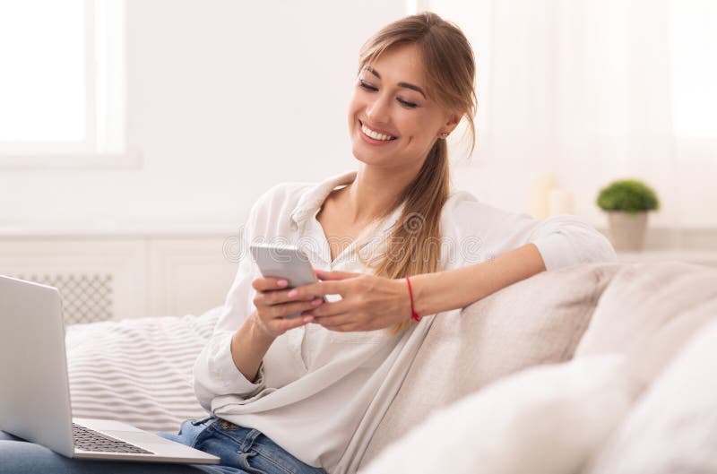 Lady Using Cellpone and Laptop Relaxing on Couch at Home Stock Photo ...