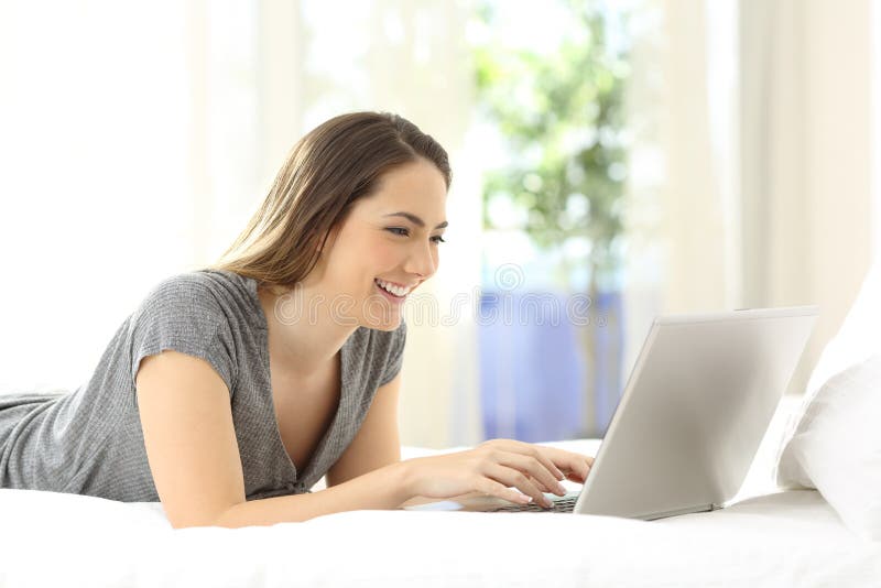 Happy lady using a laptop on the bed at home royalty free stock photos Happy lady using a laptop on the bed at home royalty free stock photos