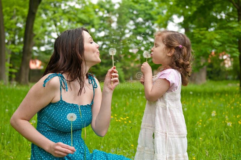 Mother with small daughter blowing to dandelion - lifestyle outdoors scene ...