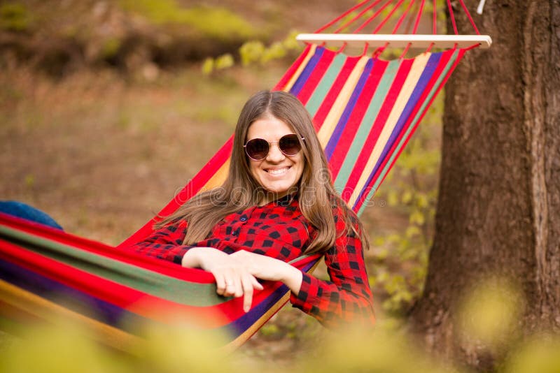 Happy lifestyle concept. Beautiful carefree woman in sunglasses in forest being happy outdoors while rest on hammock stock photos Happy lifestyle concept. Beautiful carefree woman in sunglasses in forest being happy outdoors while rest on hammock stock photos