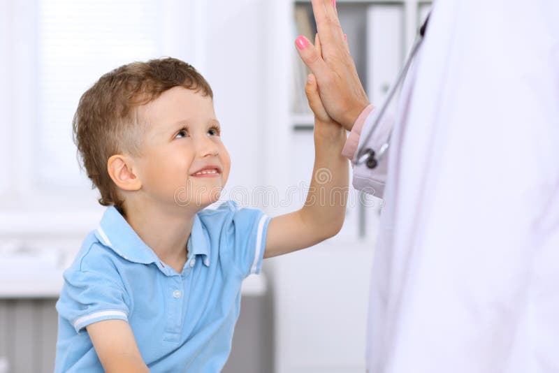 Happy little boy giving high five after health exam at doctor`s office