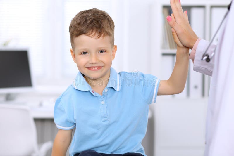 Happy little boy giving high five after health exam at doctor`s office