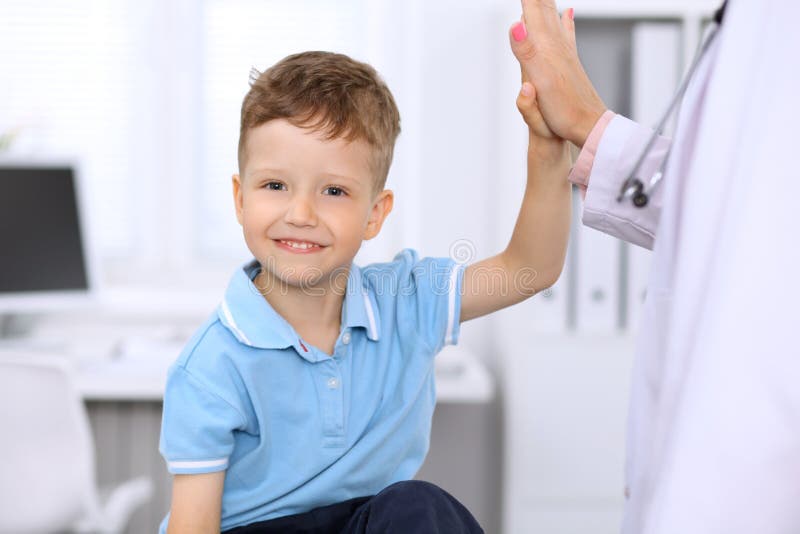 Happy little boy giving high five after health exam at doctor`s office