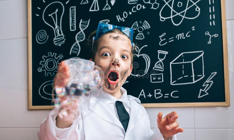 Close up of excited little scientist with dirty face holding glass with soap foam against of blackboard with drawings. Close up of excited little scientist with dirty face holding glass with soap foam against of blackboard with drawings