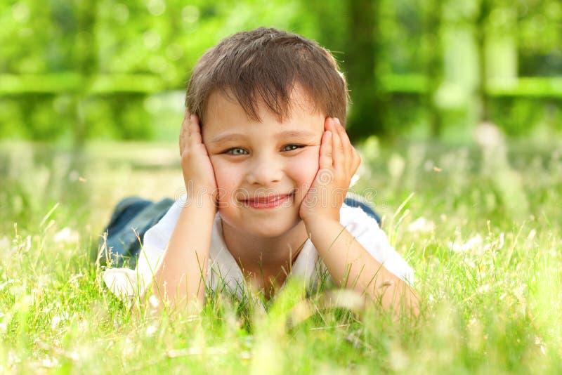 Happy little boy laying on the grass