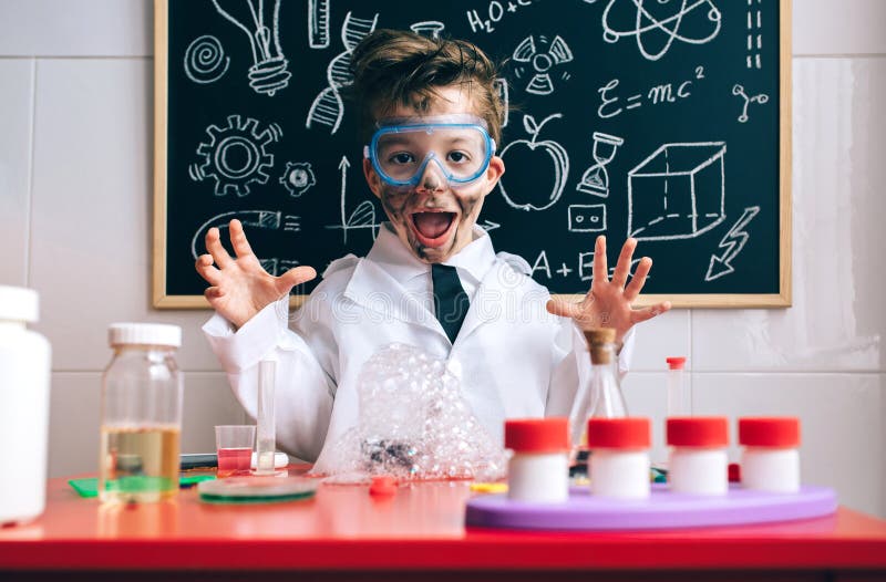 Portrait of happy little scientist with glasses and dirty face opening his arms behind of glass with soap foam over table. Portrait of happy little scientist with glasses and dirty face opening his arms behind of glass with soap foam over table