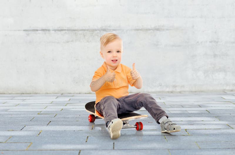 Happy little boy on skateboard showing thumbs up