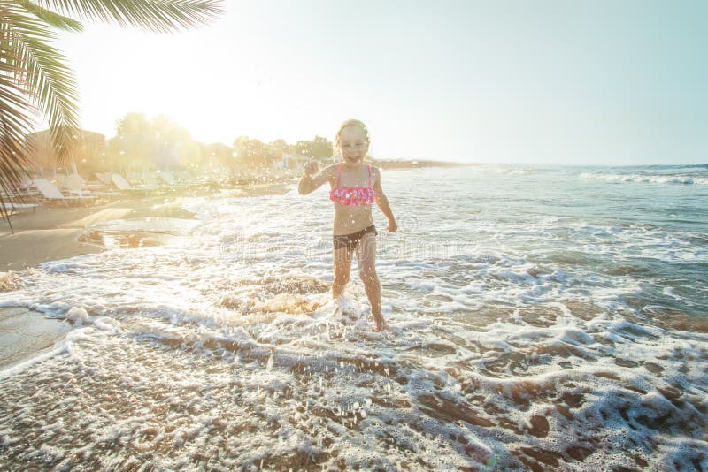 Happy little child girl playing on sea beach and having fun