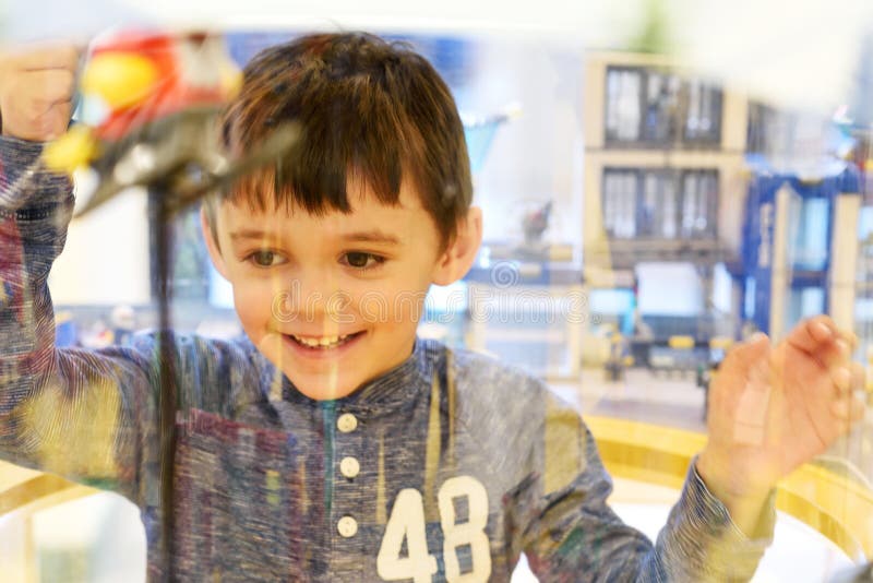 Happy little child watching toys in a shop window display royalty free stock photography