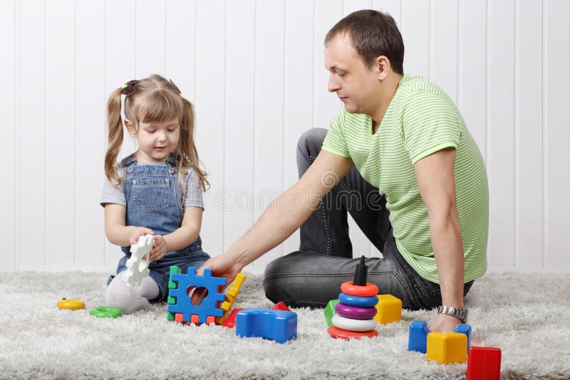 Happy little daughter and her father play toys