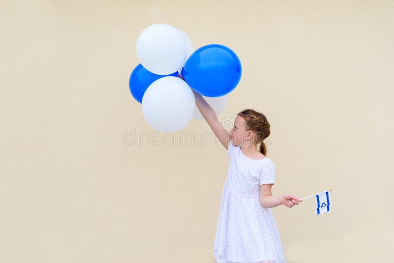 Happy little girl with blue and white balloons ans Israel flag.