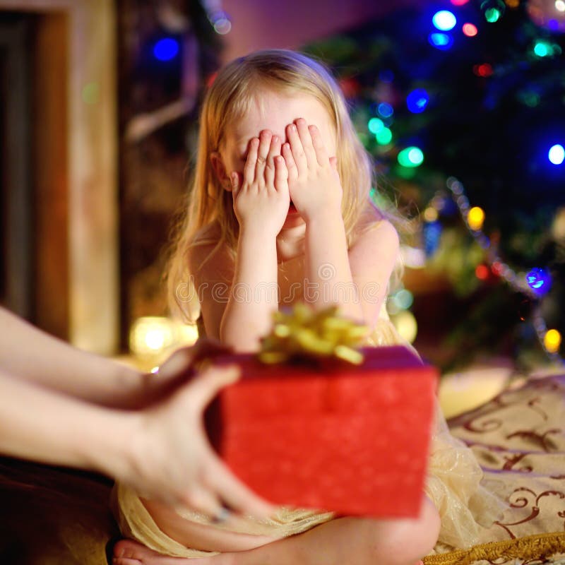 Happy little girl getting a Christmas gift from her mommy