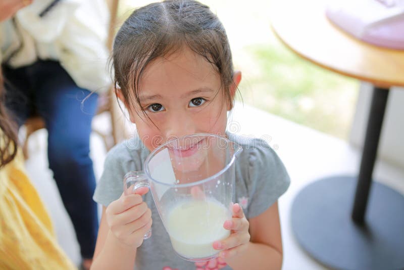 Happy little girl holding glass of fresh milk from the cows in dairy production farm royalty free stock photos Happy little girl holding glass of fresh milk from the cows in dairy production farm royalty free stock photos
