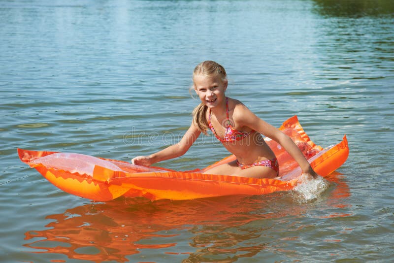 Happy little girl on mattress in lake