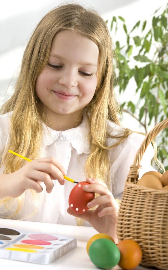 Happy little girl painting easter eggs