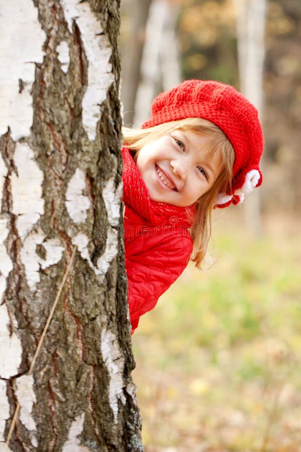 Cute happy little girl playing hide and seek outdoors