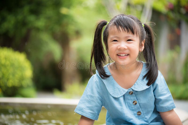 Happy little girl playing water in colorful garden on hot summer