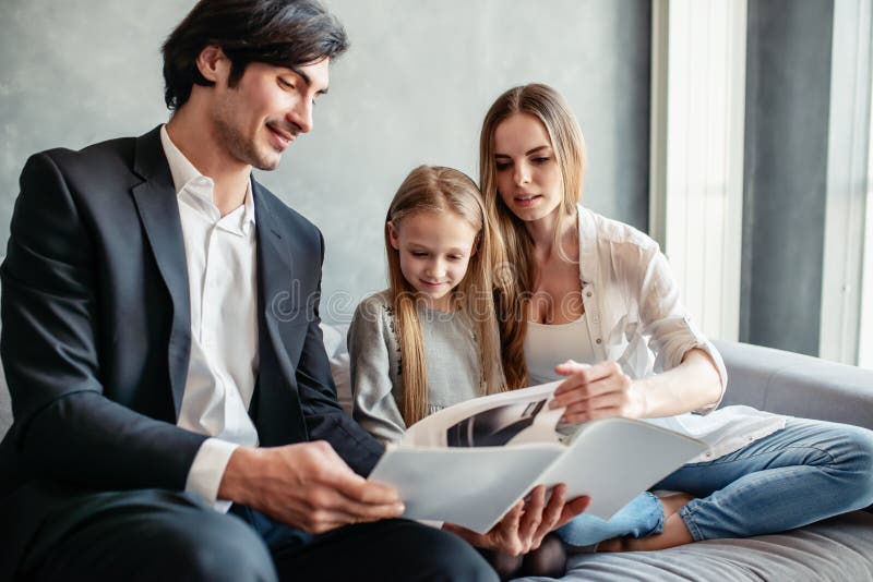 Happy little girl reads a book with her parents stock photos Happy little girl reads a book with her parents stock photos