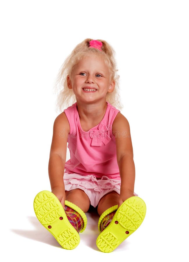 Happy little girl in rubber boots sitting on the floor isolated