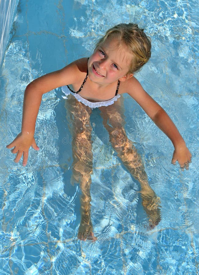 Happy little girl seat in the swimming pool.